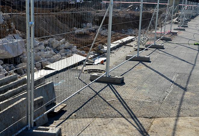 workers constructing a temporary fence with metal panels at a construction site